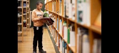 Pojke läser bok på bibliotek