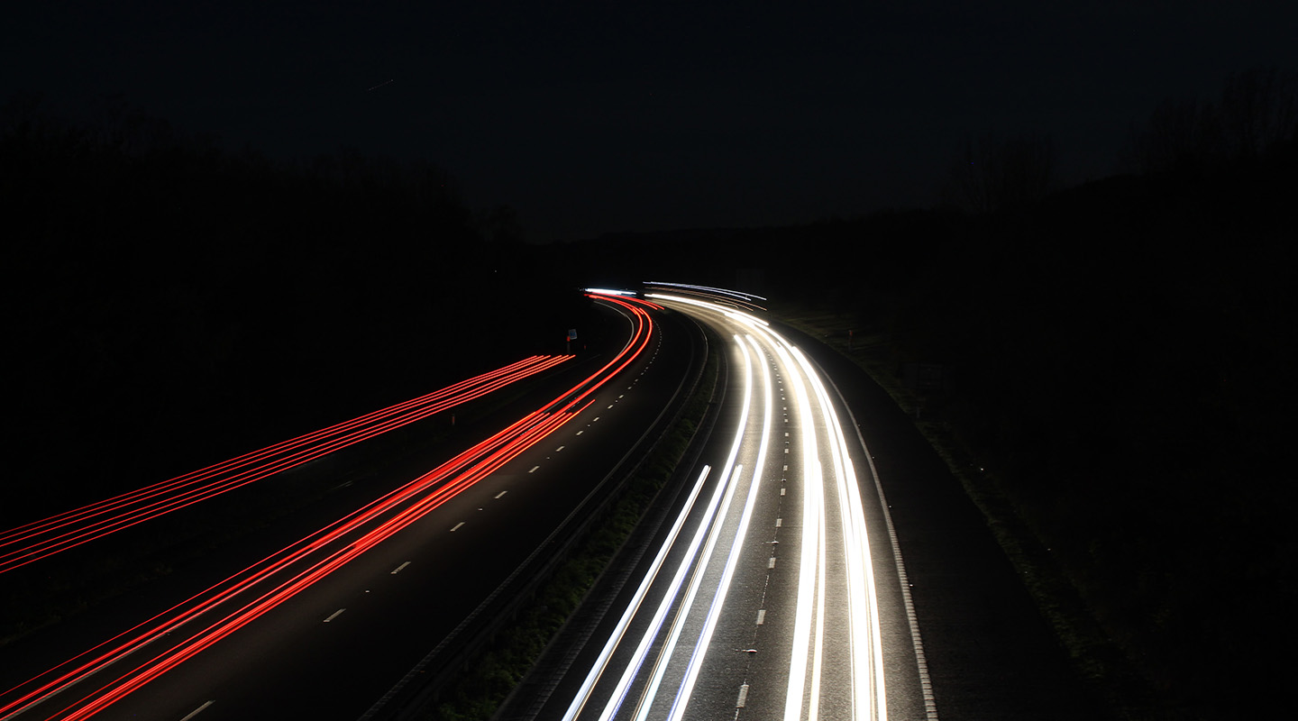 Landsväg på natten med belysning från körande bilar