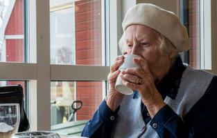 Äldre kvinna dricker kaffe.