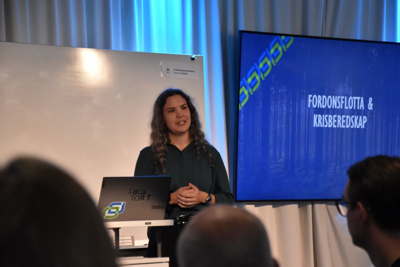 En kvinna i en föreläsningssal. I bakgrunden en presentation. I förgrunden åhörare.