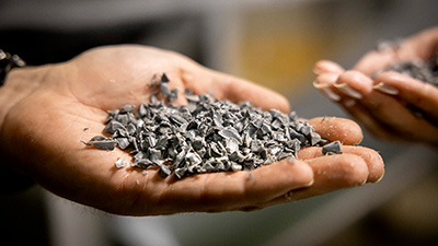 Detaljbild på en kupad hand med små bitar av plast i olika grå nyanser