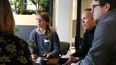 Personer vid ett fikabord sitter och diskuterar