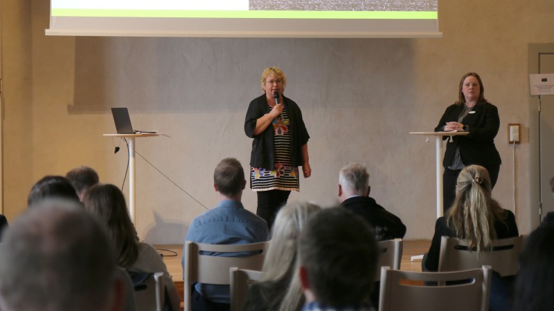 Två kvinnor på en scen. I förgrunden ser man åhörare