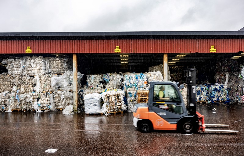 En truck kör förbi flera stora kärl för plastavfall