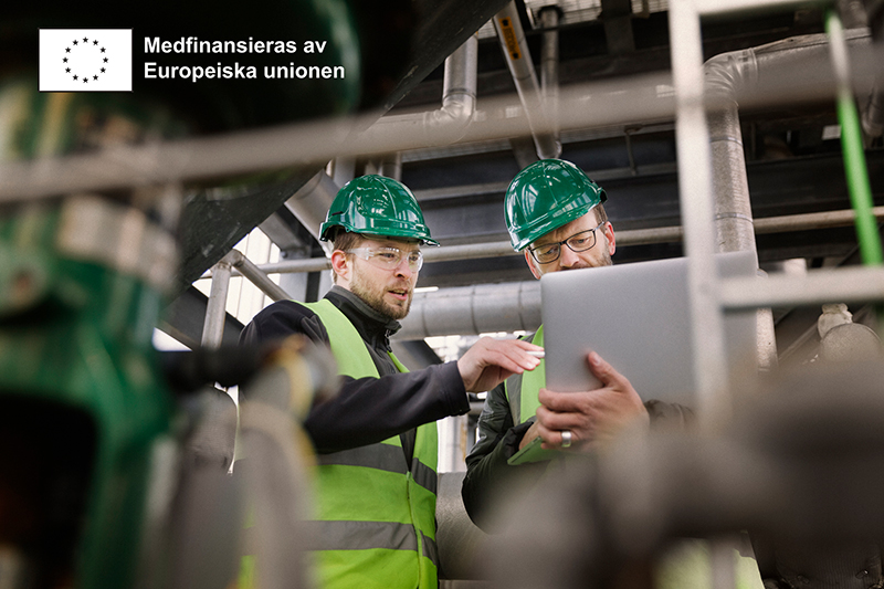 Två personer med skyddshjälmar i industrimiljö