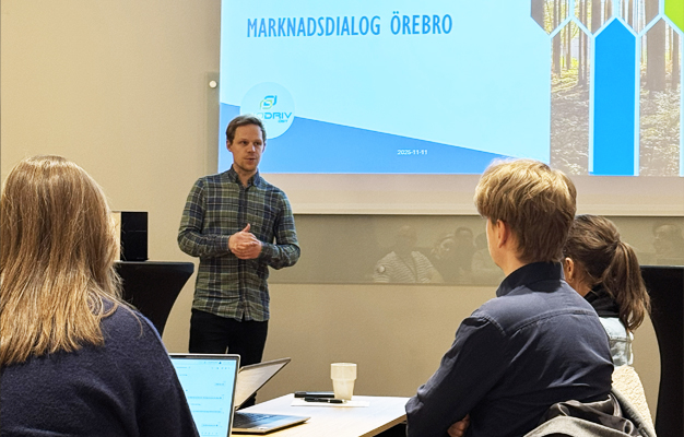 Felix Ek, som föreläsare i en grön blå rutig skjorta. Sedan ser du tre sittande personer bakifrån som lyssnar