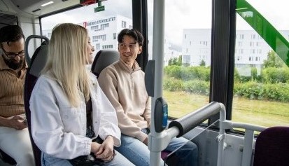 Två ungdomar sitter och samtalar inuti Citylinjens buss. I bakgrunden syns Örebro Universitet genom fönstret.