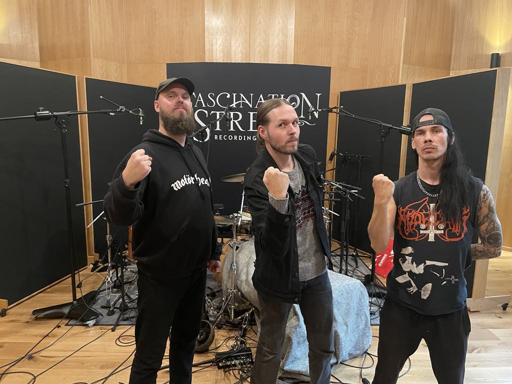 Tre personer framför trumset i musikstudio