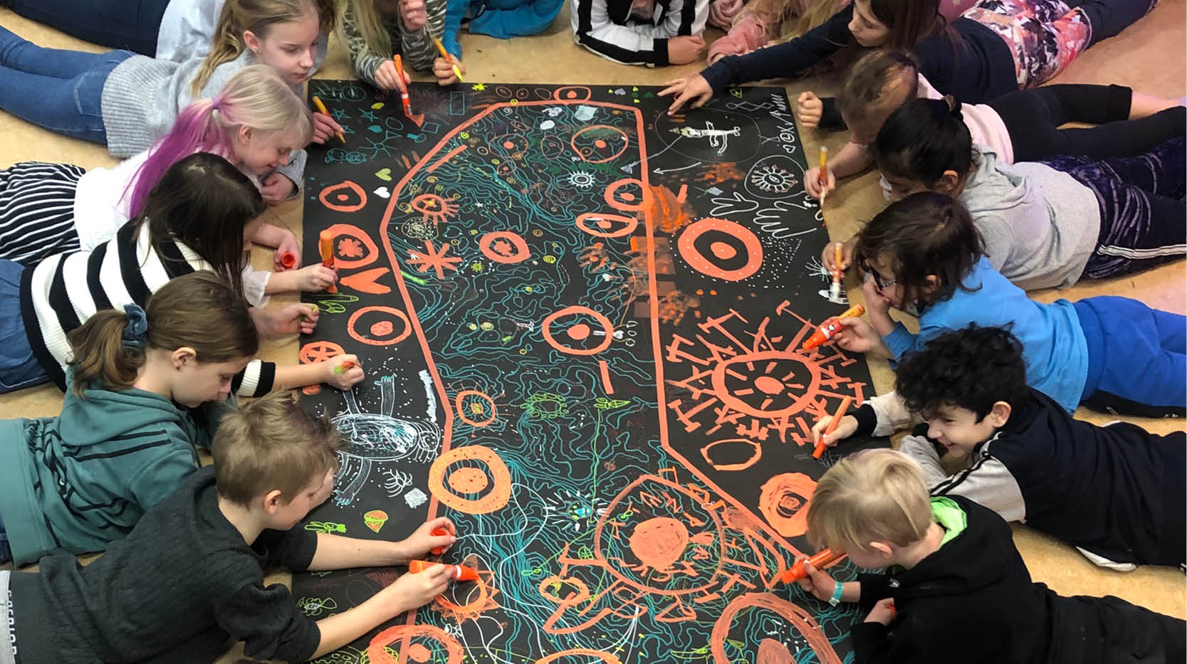 Elever i åk 3 ligger på golvet och målar på ett gemensamt, stort konstverk
