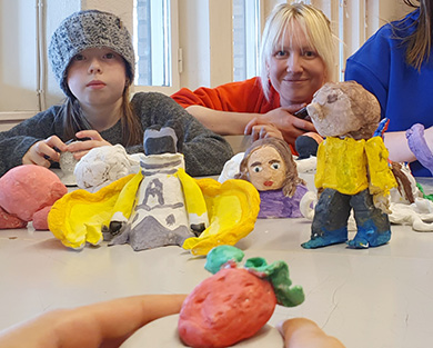 Barn och deras porträttfigurer i lera tillsammans med Hanna Stansvik