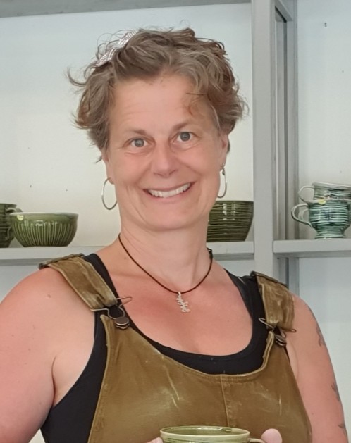 Korthårig leende kvinna med i konstnärsverkstad