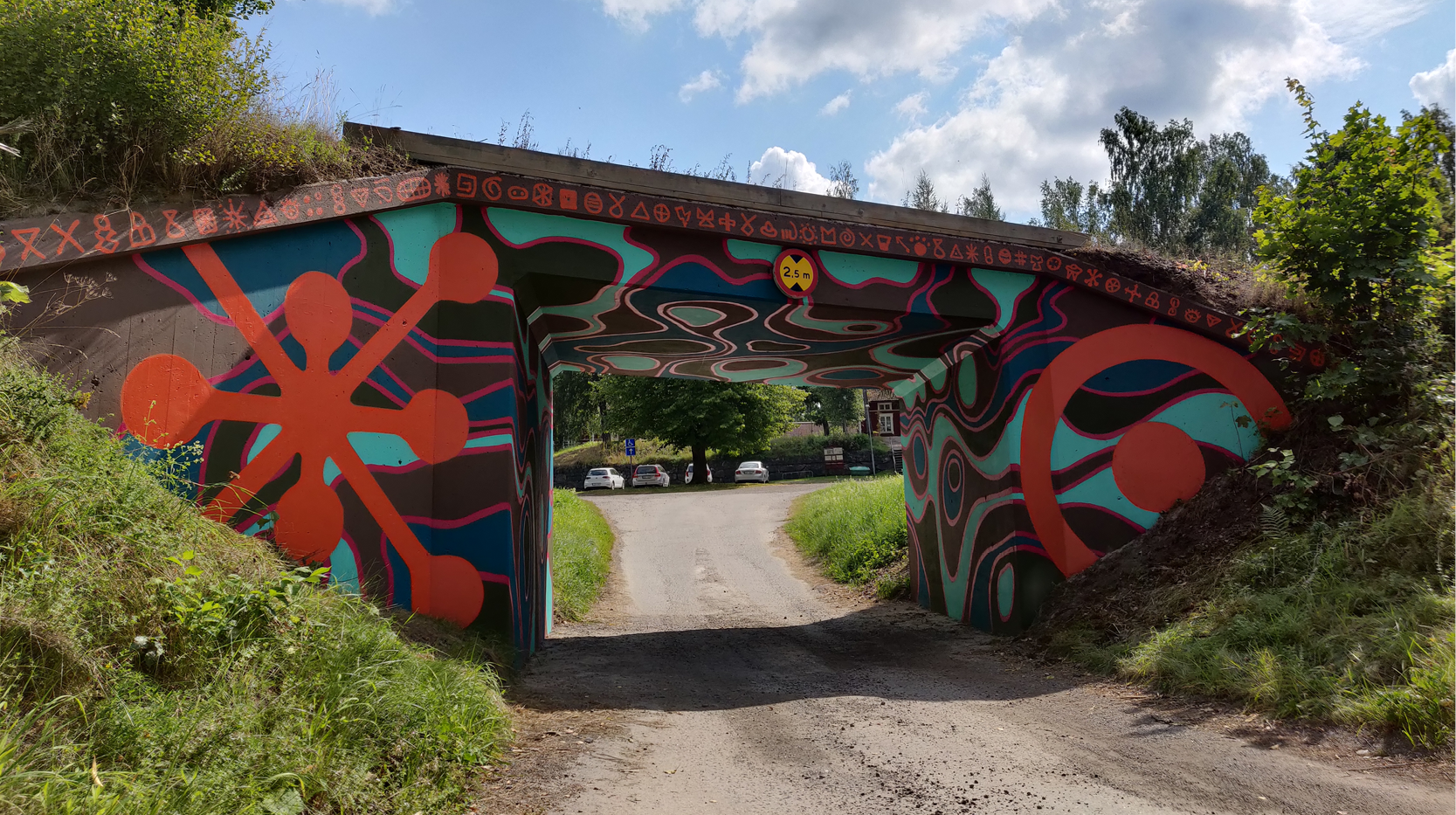 Färgglatt målad gångtunnel. På sidorna två stora symboler. Takkanten är fylld av mindre symboler.